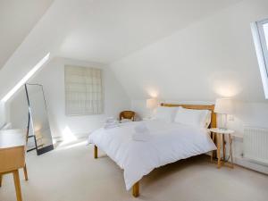 a white bedroom with a white bed and a window at Wittle Cottage in Quidenham