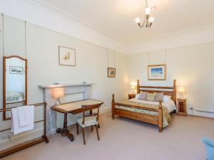a bedroom with a bed and a table and a desk at Wintonhill Farmhouse - Uk50381 in Pencaitland +18 photos