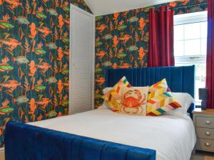 a bedroom with a bed with a blue headboard and floral wallpaper at Hyde Away - Uk50212 in Scarborough