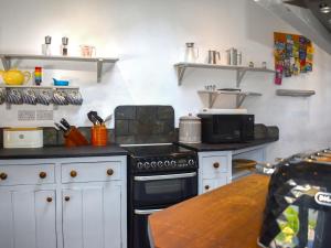 eine Küche mit Herd und Mikrowelle in der Unterkunft Manor Cottage in Ilfracombe