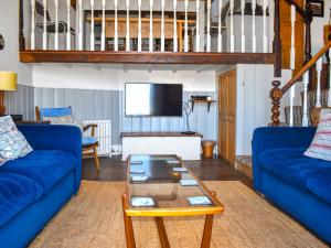 ein Wohnzimmer mit blauen Sofas und einem Fernseher in der Unterkunft Manor Cottage in Ilfracombe