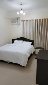 Un dormitorio con una gran cama blanca y una ventana en Golden Seasons Furnished Apartment - 2, en Salalah