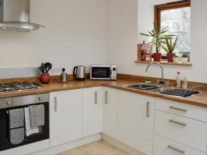 a kitchen with white cabinets and a sink at Y Gweithdy in Barmouth