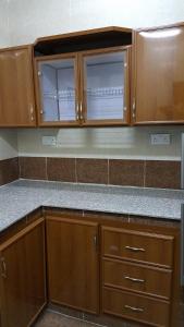 a kitchen with wooden cabinets and a counter top at Golden Seasons Furnished Apartment - 2 in Salalah