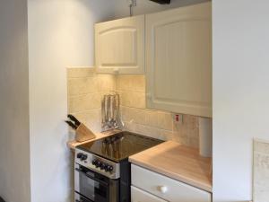 a kitchen with white cabinets and a stove top oven at Riverside Cottage in Betws-y-coed
