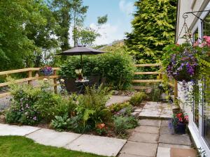 a garden with a table and an umbrella at Sandpipers in Pyworthy +4 photos