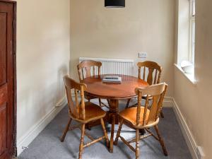 a wooden table with four chairs and a laptop on it at Rogue Cottage in Wheldrake