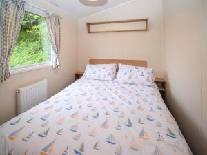 a bed in a small room with a bedspread with sailboats at Coastal Comfort in Tosside