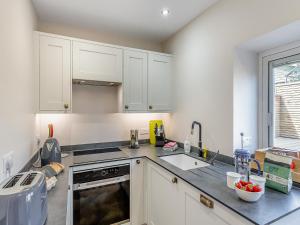 a kitchen with white cabinets and a sink at May Cottage in Luddenden Foot