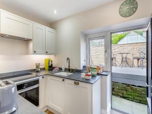 a kitchen with white cabinets and a large window at May Cottage in Luddenden Foot +13 photos