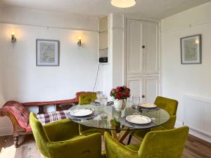 a dining room with a table and green chairs at Blue Cherry Cottage in Penrith