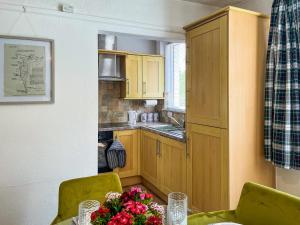 a kitchen with wooden cabinets and a table with flowers at Blue Cherry Cottage in Penrith