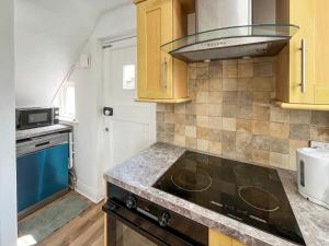 a kitchen with a stove and a microwave at Blue Cherry Cottage in Penrith