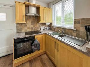 a kitchen with wooden cabinets and a sink and a stove at Blue Cherry Cottage in Penrith +8 photos