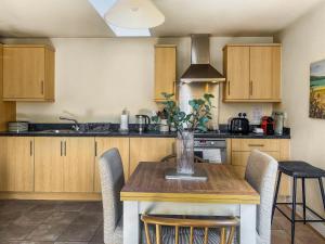 a kitchen with a wooden table with chairs and a vase on it at Coach House Apartment in Bournemouth