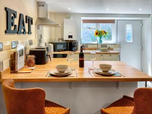 a kitchen with a table with two glasses of wine at The Old Posthouse Barn - Uk50191 in Badgworth