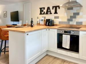 a kitchen with white cabinets and an eat sign on the wall at The Old Posthouse Barn - Uk50191 in Badgworth