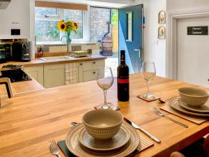 a table with a bottle of wine and two glasses at The Old Posthouse Barn - Uk50191 in Badgworth +11 photos