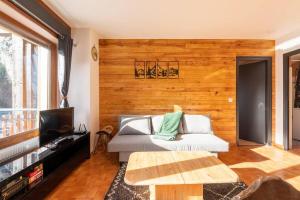 ein Wohnzimmer mit einem Sofa und einer Holzwand in der Unterkunft Le petit Schuss in La Giettaz