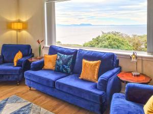 a living room with two blue couches and a large window at Sunny Hill - Ukc6884 in Aultgrishin
