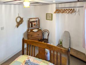 a bedroom with a crib and a dresser and a mirror at Wee Cottage in Paignton +8 photos