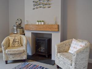 ein Wohnzimmer mit zwei Stühlen und einem Kamin in der Unterkunft Albion Cottage in Pakefield