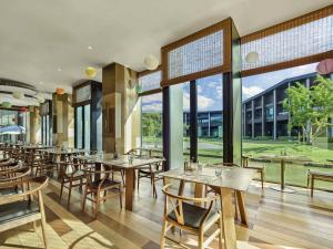 een restaurant met tafels en stoelen en grote ramen bij Pullman Kaifeng Jianye in Kaifeng