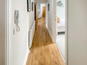 a hallway leading to a bedroom with white walls and wood floors at Low Tide - Uk50362 in Filey +4 photos