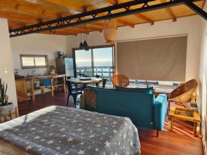 a bedroom with a bed and a table and a kitchen at Cabañas Refugio Costero in Pelluhue