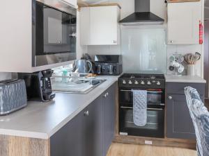a kitchen with gray cabinets and a stove top oven at The Laughing Seagull - Uk50213 in Aberystwyth +9 photos