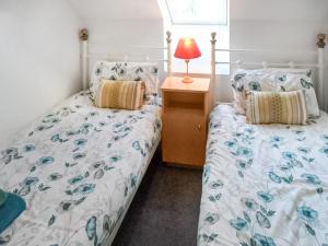 a bedroom with two beds and a lamp on a night stand at Blackfriars in Wroxham