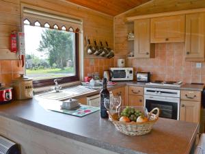 eine Küche mit einem Obstkorb und einer Flasche Wein in der Unterkunft Hartland Forest Golf & Leisure in Woolfardisworthy