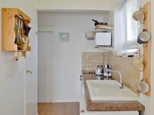 Una pequeña cocina con fregadero y ventana. en On The Beach, en Ventnor