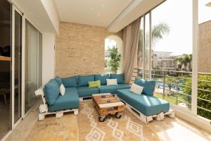 Una sala de estar con un sofá azul y una mesa. en Welcome to Tamaris Escape 2BR Sea & Vue Piscine, en Dar Mohammed Ould Haj Jilali