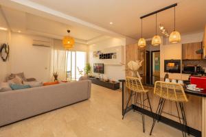 Una sala de estar con un sofá y una cocina. en Welcome to Tamaris Escape 2BR Sea & Vue Piscine, en Dar Mohammed Ould Haj Jilali