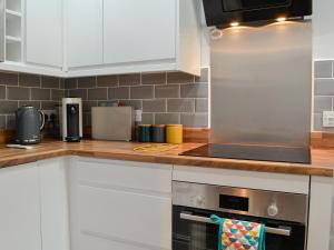 a kitchen with white cabinets and a stainless steel refrigerator at Howbeck Cottage in Hesket Newmarket +12 photos