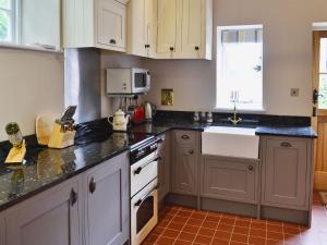 a kitchen with gray cabinets and a white stove top oven at The Coach House The Old Rectory in Buckland St Mary