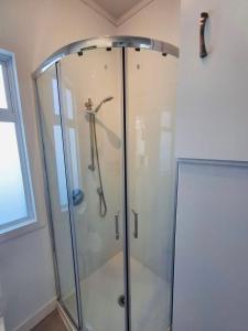 a shower with a glass door in a bathroom at The cottage coghill in Whitianga
