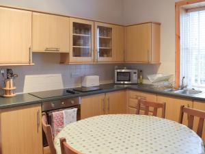 una cucina con mobili in legno e un tavolo con un tableablish di Kilfillan Cottage a Garlieston Altre 10 foto
