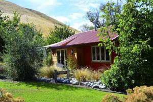 Burn Cottage Retreat في كرومويل: منزل احمر صغير بسقف احمر