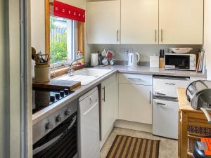 a kitchen with white cabinets and a sink at Isla's Cottage in Nairn