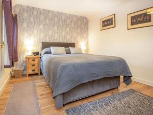 a bedroom with a large bed and a night stand at Isla's Cottage in Nairn +5 photos