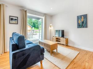 a living room with a blue couch and a tv at Hole Farm - Stable Cottage in Shootend