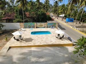 a swimming pool with chairs and umbrellas next to a road at Pousada Plenamar in Maragogi