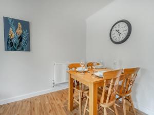 a dining room table with chairs and a clock on the wall at Hole Farm - Stable Cottage in Shootend