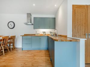a kitchen with blue cabinets and a table at Hole Farm - Stable Cottage in Shootend