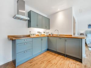 a kitchen with blue cabinets and a wooden floor at Hole Farm - Stable Cottage in Shootend