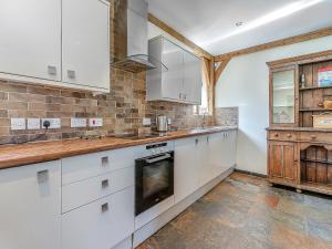 a kitchen with white cabinets and a stove top oven at Y Llaethdy - Uk49916 in Penclawdd