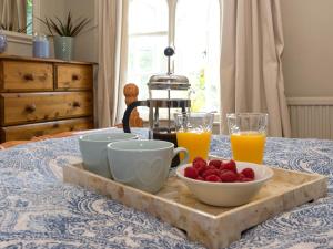a table with a tray with a bowl of fruit and orange juice at Dell Cottage in Mundesley +18 photos