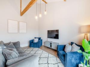 a living room with blue couches and a tv at The Coach House in Whittonstall